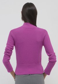 Maglione viola aderente con colletto alto, polsini e orlo a costine. Texture morbida, maniche lunghe, senza motivi visibili o dettagli in metallo.