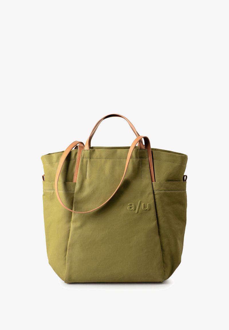 Olivegrüne Tragetasche mit Ledergriffen, minimalistisches Design, Seitentaschen und geprägtem Logo auf der Vorderseite.