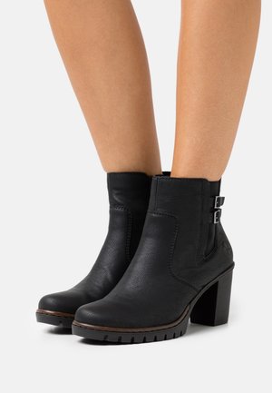 Bottines noires en cuir avec une finition texturée, bout carré et talon bloc. Comporte deux boucles en métal argenté sur les côtés et une semelle en caoutchouc.