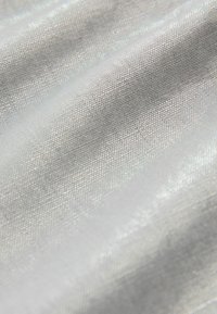 Ezüst, áttetsző szövet sima felülettel és finom szövésű mintával, amely diszkrét fényességgel és könnyű jellemzőkkel rendelkezik.