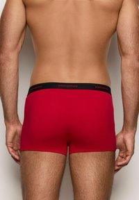 Bóxer rojo con cintura negra que presenta el logo "yamamay" en rojo. La tela parece suave y ajustada, con un diseño sencillo.