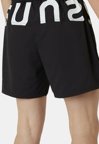 Pantaloni da bagno neri con una cintura elastica, caratterizzati da un grande testo bianco sul retro. Il tessuto è liscio e leggero.