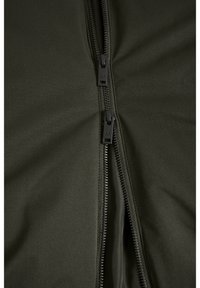 Grüne Zip-Jacke mit zwei schwarzen Reißverschlüssen, glattem Stoffgefühl und einer taillierten Passform mit leichtem Glanz.