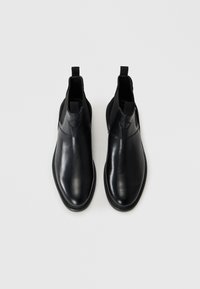 Black leather ankle boots with elastic side panels, smooth surface, rounded toe, and pull tabs for easy wear.