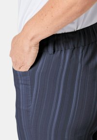 Marine gestreepte broek met een gladde textuur, elastische tailleband, zijzakken en smalle lichtblauwe verticale lijnen.