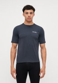 Maglietta a maniche corte di colore grigio scuro realizzata in tessuto leggero, con una texture sottile e il logo bianco "LE COL" sul lato sinistro del petto.