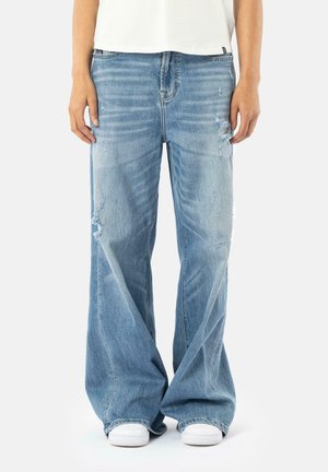 Light blue wide-leg jeans with a distressed design, featuring rips and faded areas, made of denim, paired with white sneakers.