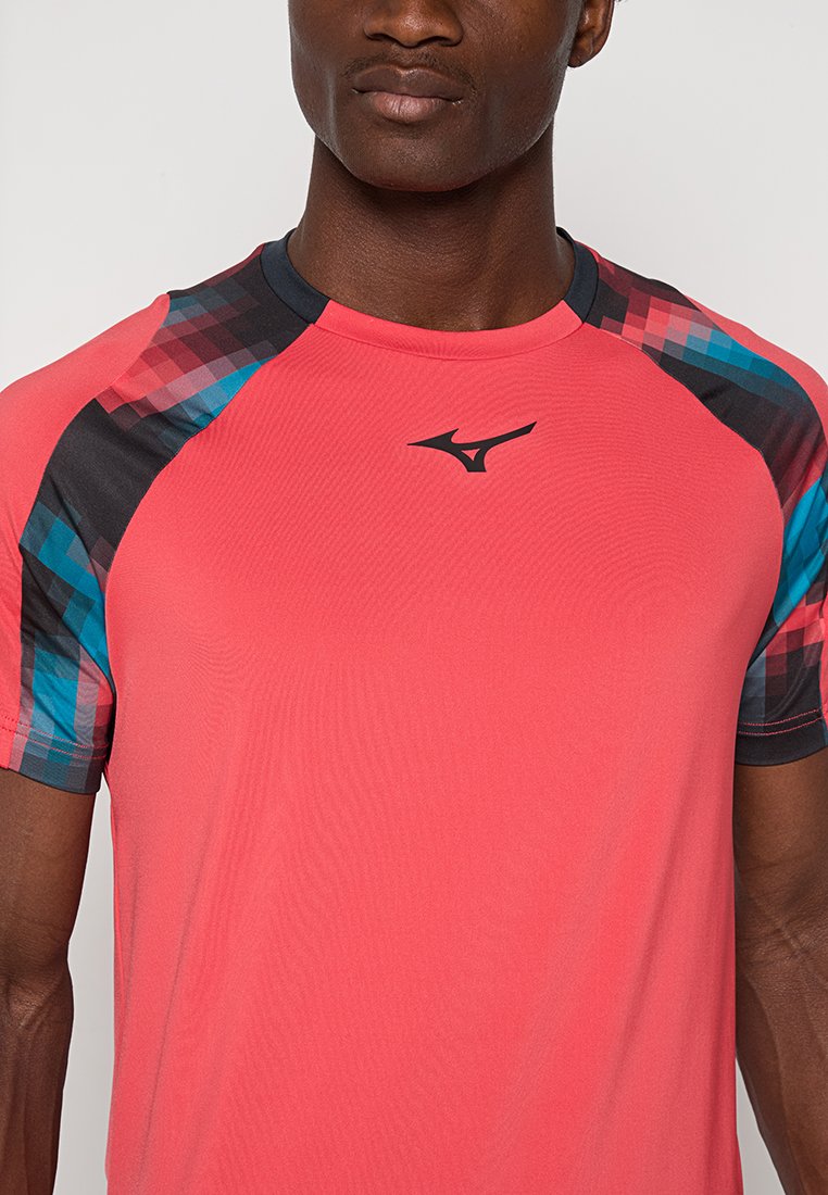 T-shirt de sport ajusté en rose vif, avec des motifs géométriques colorés sur les épaules et un petit logo noir sur la poitrine.