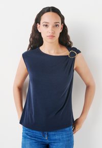 Navy blue short-sleeve top with a round neckline, featuring a gold ring accent on one shoulder. Smooth fabric, relaxed fit.