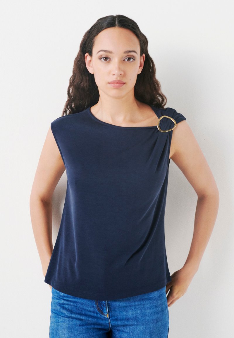 Navy blue short-sleeve top with a round neckline, featuring a gold ring accent on one shoulder. Smooth fabric, relaxed fit.