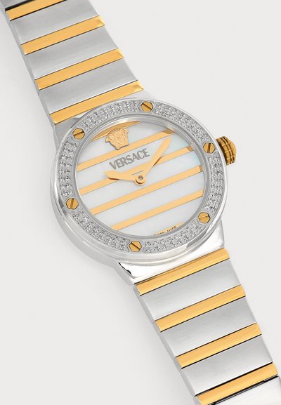 Montre-bracelet Versace en argent et or avec cadran rayé, aiguilles dorées, lunette sertie de diamants et logo Méduse à 12 heures.