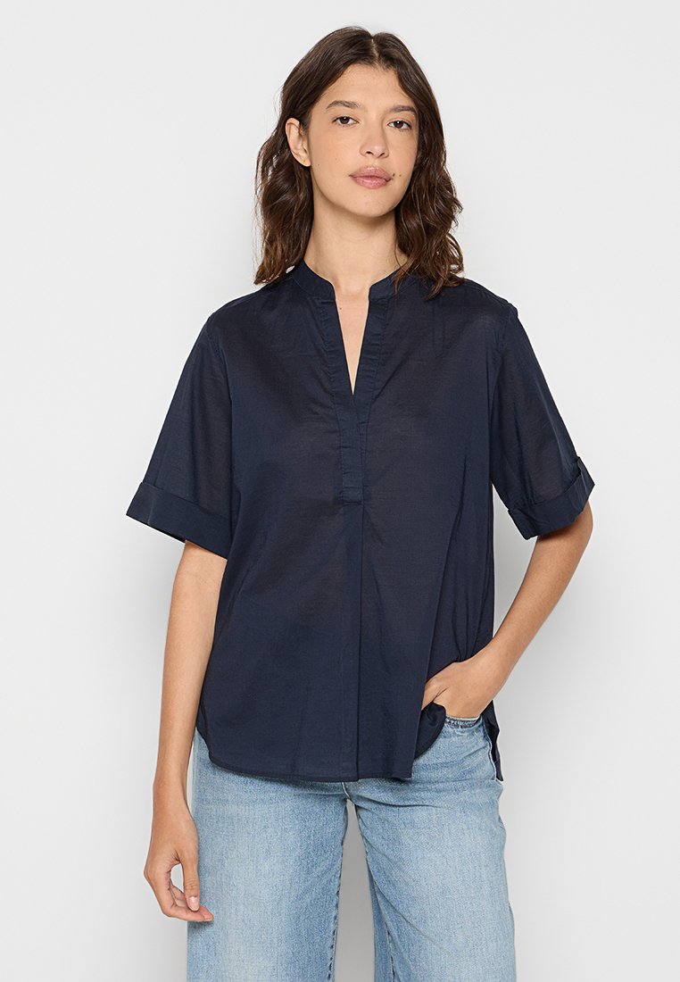 Navyblaues Kurzarmhemd mit Stehkragen, featuring eine frontale Knopfleiste und hochgekrempelte Ärmel, aus einem glatten, leichten Stoff gefertigt.