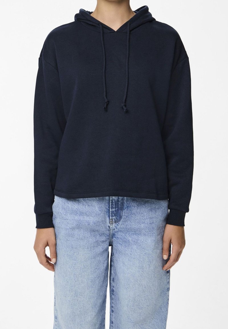 Marinblå hoodie i mjukt tyg med V-ringning, dragsko i huvan och avslappnad passform. Kombinerad med ljusblå vida jeans.