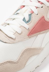 Sneaker con una toma in rete color crema testurizzata, con morbidi dettagli in suede beige, particolari rosa e blu, e lacci bianchi.