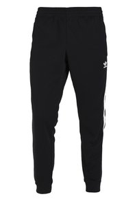 Svarta träningsbyxor av mjukt tyg, med elastiskt midjeband och vita sidostreck, samt en liten logotyp på vänster lår.