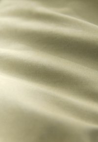 Material textil galben deschis cu o textură fină, prezentând pliuri delicate și un luciu ușor, predominant într-un model solid.