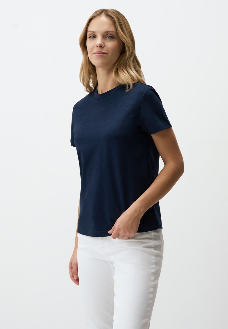T-shirt blu navy a maniche corte realizzato in tessuto morbido, con scollo rotondo e vestibilità comoda, abbinato a pantaloni bianchi.