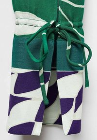 Tissu à motifs verts, blancs et violets avec un cordon vert noué en nœud au centre.