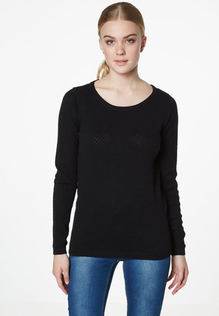 Pull noir à manches longues avec un col rond et un tricot texturé, affichant des motifs horizontaux subtils. Associé à un jean bleu.