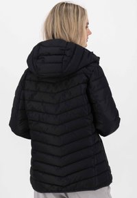 Schwarze Puffyjacke mit Kapuze, ausgestattet mit einem Zickzack-Quiltmuster und elastischen Bündchen. Glatte Textur mit mittellangem Schnitt.