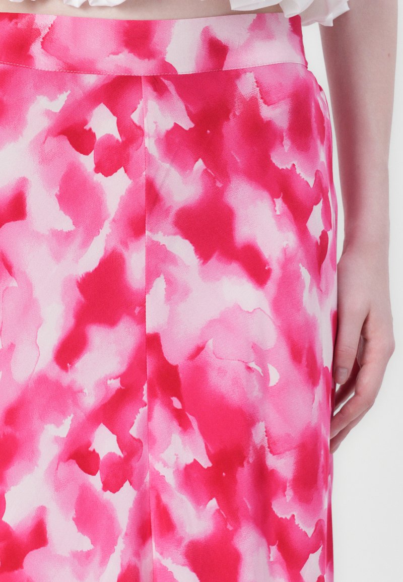 Une jupe fluide rose avec un motif aquarelle dans des nuances de rose clair et foncé, texture lisse, et une taille au bord supérieur.