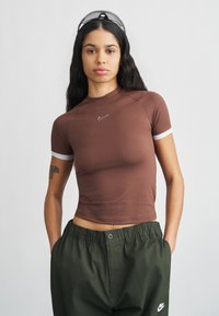 Καφέ κοντομάνικη μπλούζα με εφαρμοστή σχεδίαση και λευκές λεπτομέρειες. Διαθέτει μικρό λογότυπο Nike στο στήθος. Συνδυασμένη με άνετο σκούρο πράσινο παντελόνι.