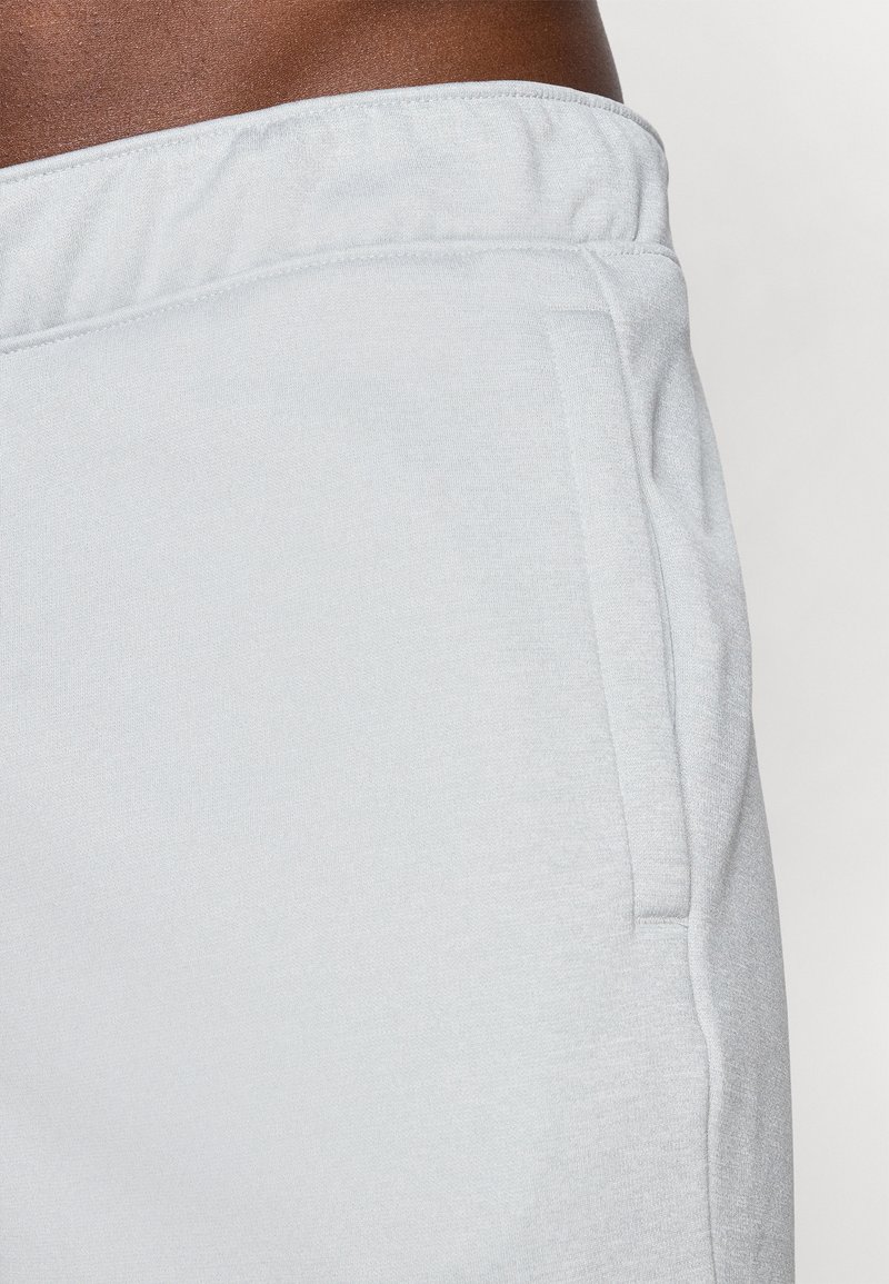 Pantalons de jogging gris clair avec une taille élastique, détail de poche latérale et une texture douce. Aucun motif ou accent visible.