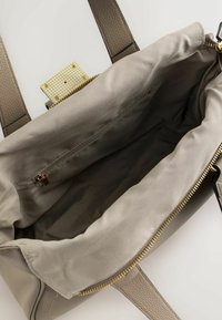 Harmaa nahkainen käsilaukku, jossa on teksturoitu pinta, päältä vetoketjullinen suljin ja sileä kangasvuori. Laukussa on vetoketjutasku ja kullanväriset metalliosat.