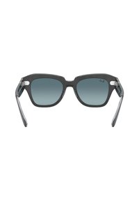 Gafas de sol de plástico gris con lentes rectangulares, tintado degradado y acentos metálicos en las patillas. Diseño elegante con bisagras resistentes.