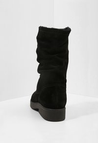 Černé nubukové kotníkové boty se sklopeným designem, plochou podrážkou a kontrastním prošíváním. Interiér je podšitý měkkým materiálem.
