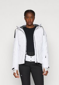 Fehér puffermellény cipzárral, állítható kapucnival és elasztikus mandzsettával. Állapota steppelt textúrájú, fekete részletekkel a ujjakon és a cipzáron.