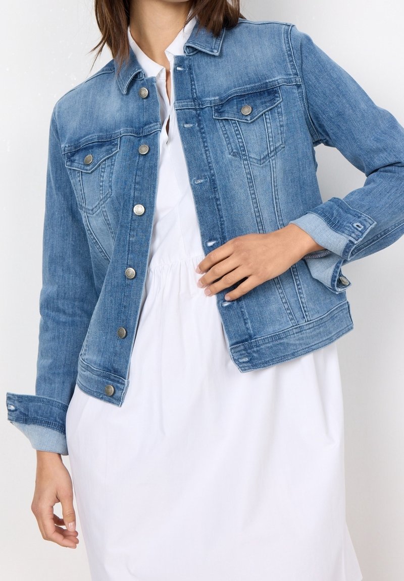 Vaikka sininen farkkutakki, jossa on etutaskut, napitus ja käännetyt hihat. Suora pinta ja klassinen muotoilu.