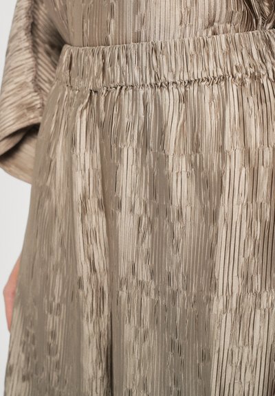 Plisserte midiskjørt i lys beige satin med elastisk midje; har vertikal tekstur og myk glans.