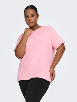 T-shirt rosa a maniche corte in morbido cotone, con vestibilità ampia e orlo dritto. Il modello è posizionato davanti a uno sfondo grigio chiaro.