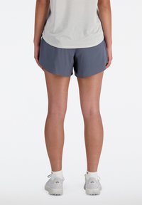 Graue Sportshorts mit lockerer Passform und atmungsaktivem Material, kombiniert mit einem hellgrauen Oberteil, von hinten betrachtet.