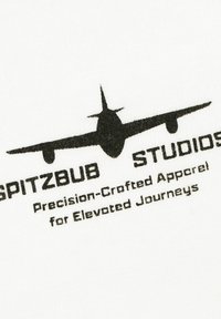 White fabric featuring a black logo of an airplane and text: "SPITZBUB STUDIOS Precision-Crafted Apparel for Elevated Journeys."