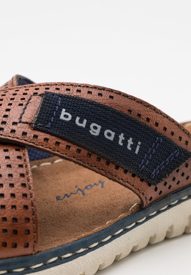Braune Ledersandale mit perforiertem Design, navyfarbener Stoffriemen mit "bugatti"-Logo und beiger Gummisohle mit strukturiertem Grip.