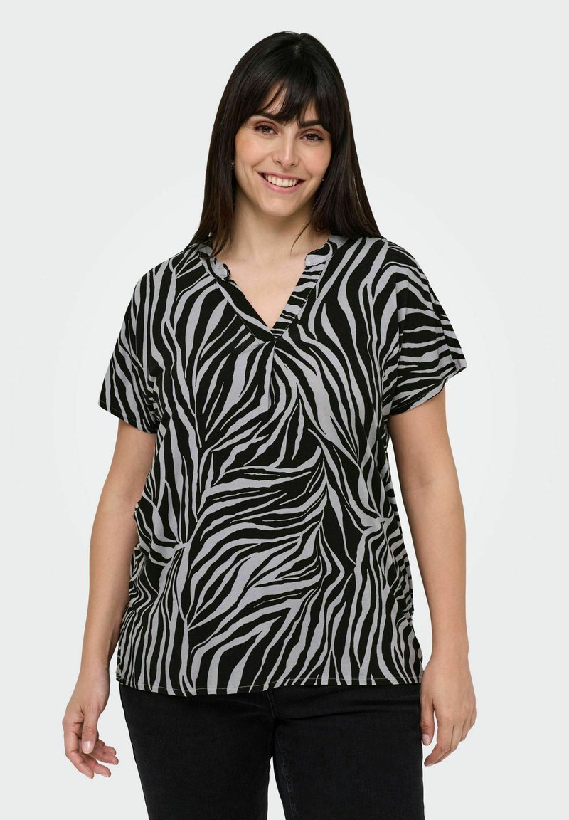 Svart och grå t-shirt med zebramönster, v-ringning och korta ärmar. Mjuk tyg, avslappnad passform, påfallande kontrasterande mönster.