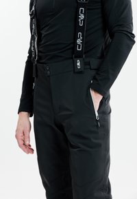 Sorte skibukser med justerbare stropper, lynlåsede lommer og en glat, tekstureret finish. Har to knapper i taljen.