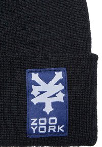Căciulă tricotată neagră cu un patch logo dreptunghiular albastru, ce prezintă un design alb și textul "ZOO YORK" în partea de jos.