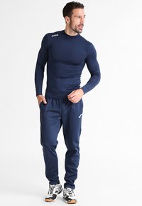 Marine langærmet atletisk skjorte i slim fit, parret med matchende marine joggers. Har logo på skjorten og joggers. Stribet tekstur.