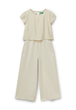 Mono de color crema con parte superior de manga corta y corte cuadrado, y pantalones de pierna ancha con bolsillos laterales. Tejido suave con un brillo sutil.