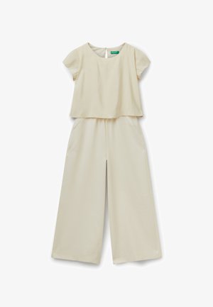 Mono de color crema con parte superior de manga corta y corte cuadrado, y pantalones de pierna ancha con bolsillos laterales. Tejido suave con un brillo sutil.