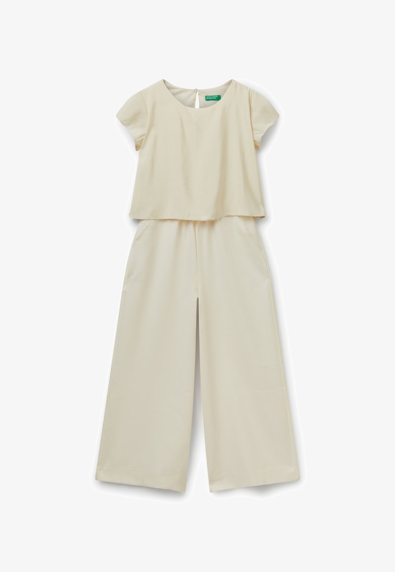 Crèmekleurige jumpsuit met een kortmouwige, boxy top en wijde broekspijpen met zijzakken. Gladde stof met een subtiele glans.