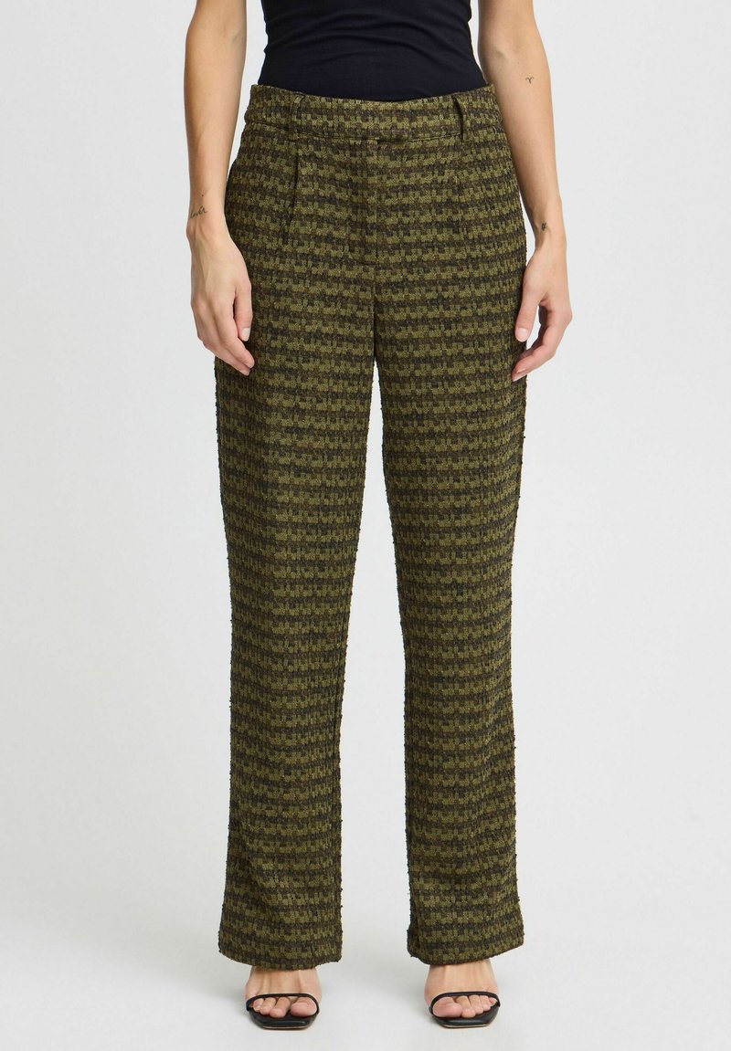 Pantalons à carreaux verts avec une coupe décontractée, en tissu texturé, taille mi-haute et plis à l'avant, associés à un haut noir et des sandales.