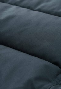 Temno siva oblazina iz tkanine s gladko teksturo in prešito zasnovo z diskretnimi črtami in šivi.