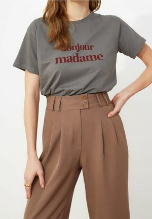 Szara bawełniana koszulka z napisem "bonjour madame" w kolorze bordowym. Brązowe spodnie z wysokim stanem, z zakładkami i dwoma guzikami z przodu.