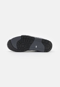 Talpa de sneaker în cauciuc negru și gri, cu textură nervurată și modele de profil pronunțate pentru aderență și durabilitate.