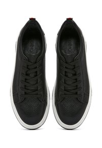 Sneaker in pelle nera con superficie texturizzata, design con lacci, suola in gomma bianca e dettagli rossi sul tallone.