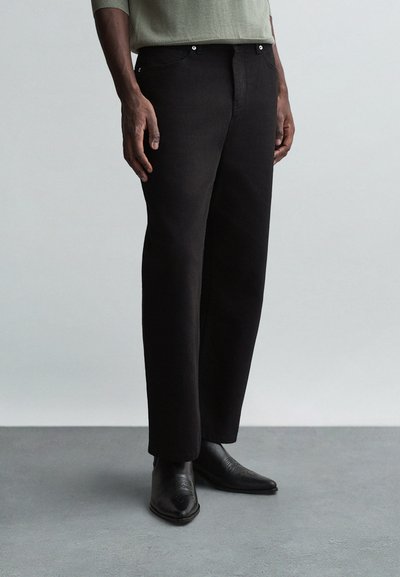 Zwarte denimbroek met een rechte pasvorm, vijf-pocketdesign en zilveren accessoires. Gemaakt met puntige zwarte leren laarzen.
